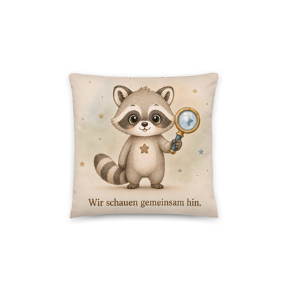 Cremefarbenes Raxi-Dekokissen mit Waschbär, blau-goldener Nachtlupe und dem Spruch Wir schauen gemeinsam hin.