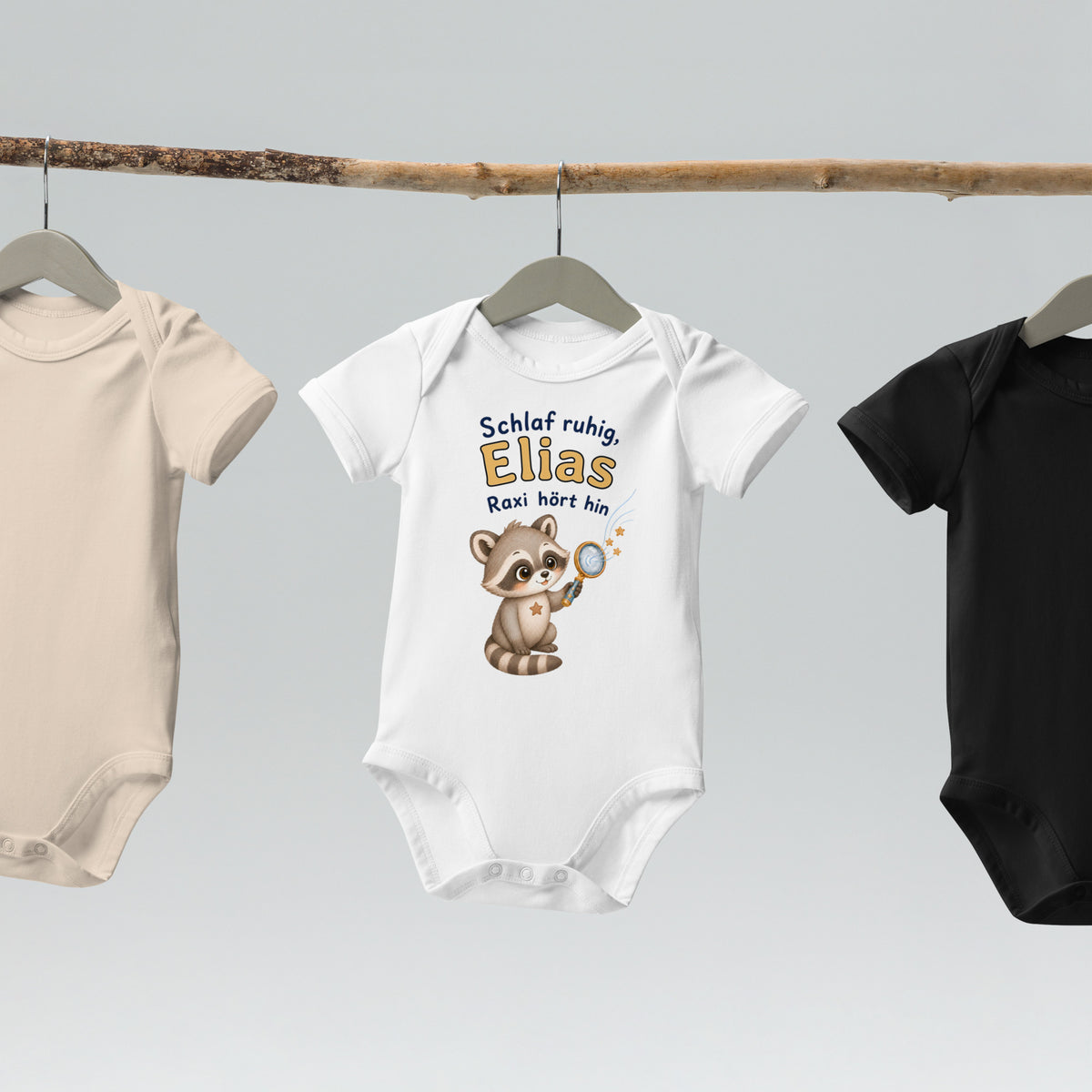 weißfarbener personalisierter Raxi-Babybody hängend